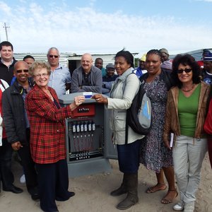 Burgemeester Nicolette Botha-Guthrie en Raadslid Theodorah Nquinata, omring deur raadslede, munisipale beamptes en die kontrakteurs tydens die seremonie met die aanskakeling van elektrisiteit vir 85 informele wonings in Masakhane